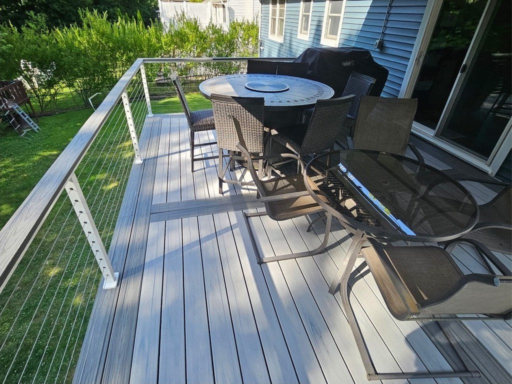 Upper composite deck arranged for dining, with cable railing overlooking the yard.