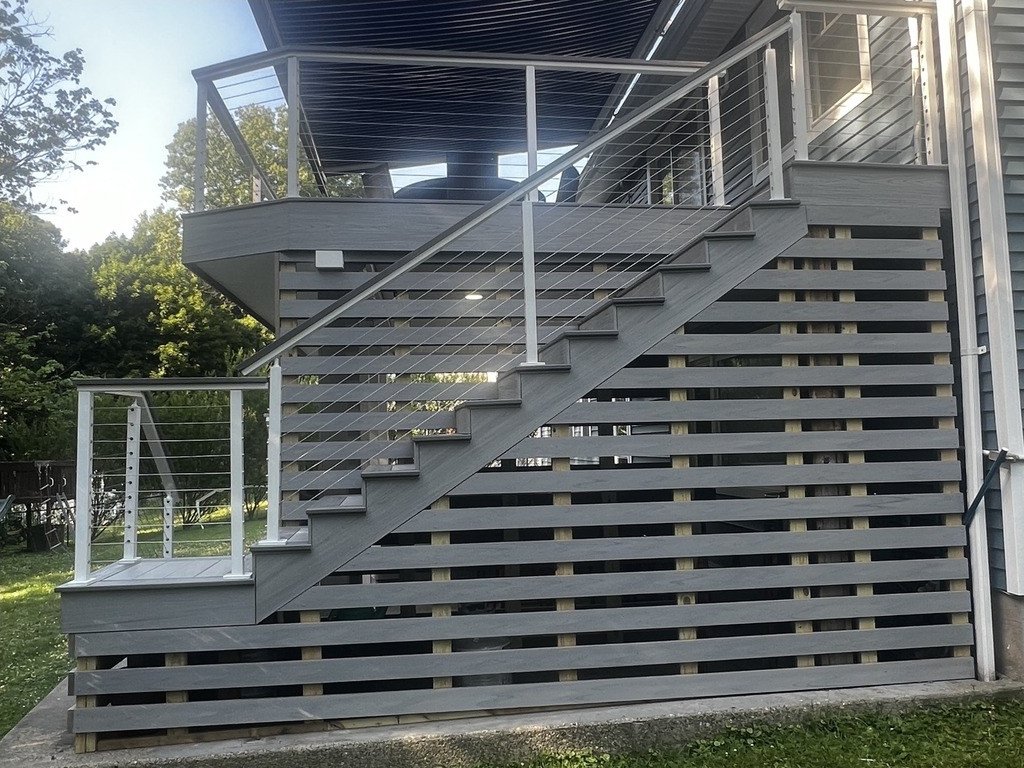 Custom stair tower with horizontal composite skirting and cable railing.