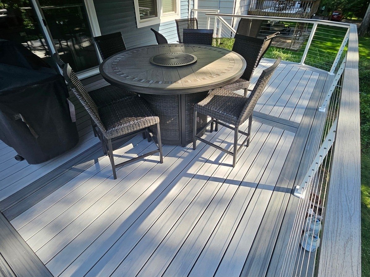 Composite deck dining area with cable railing and coordinated outdoor furnishings.
