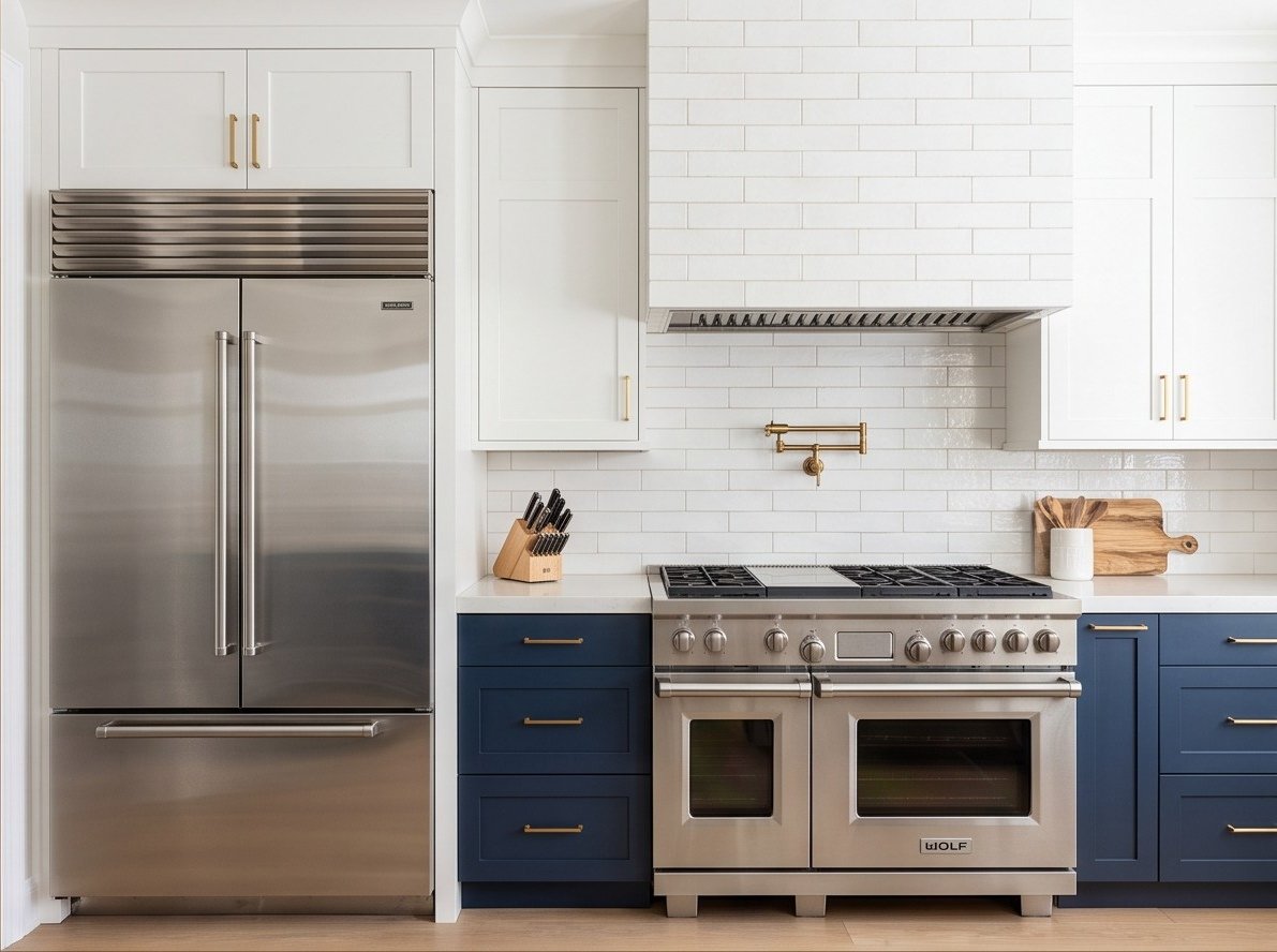 Professional range wall with stainless refrigerator, white cabinetry, and textured tile backsplash.